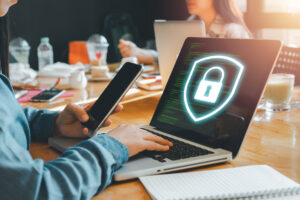 Person, die auf der Computertastatur und dem Handy tippt, um einen sicheren Internetzugriff und Datenschutz vor Hackern zu gewährleisten und den Server vor Cyberkriminalität zu schützen.